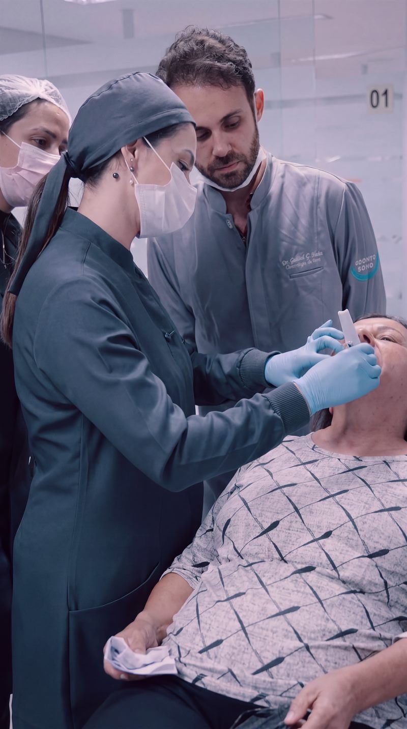 Dra. Thays Crosara e equipe avaliando a paciente na cadeira odontológica